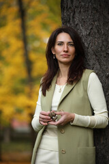 Elegant woman standing by tree in autumn park