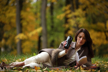 Woman Reading a Book Outdoors in Autumn Park
