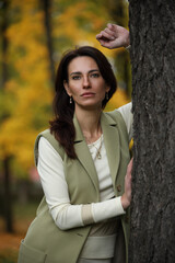 Elegant woman standing by tree in autumn park