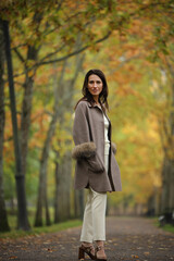 Elegant woman walking through colorful autumn park pathway