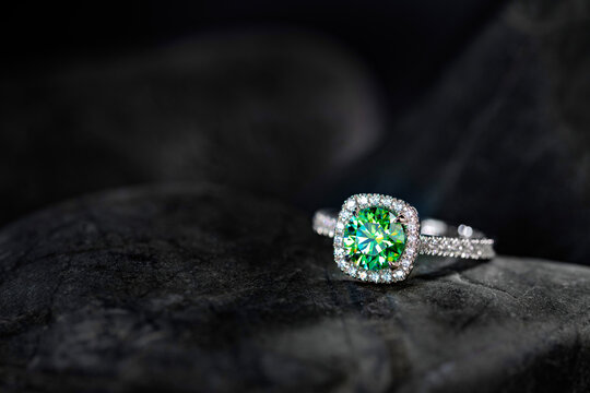 A green diamond ring sits on a black stone