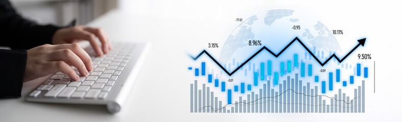 A close-up image showing hands typing on a keyboard with graphs and statistics in the background,...