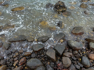 Photograph of a group of pebble rocks on the beach breaking ocean waves