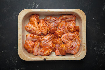 Raw marinated chicken wings spices red sauce paprika baking tray cooking top view