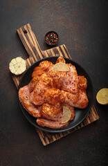 Raw marinated chicken wings spices garlic lemon black plate wooden cutting board cooking
