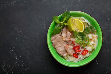 Vietnamese pho bo noodle soup beef lime asian bowl dinner black background top view copy space