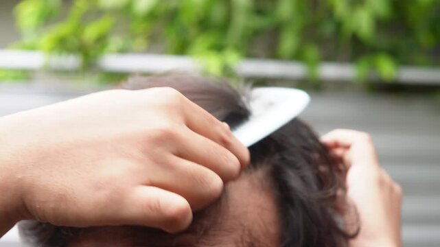 A man combing his messy hair. Does not show the face.