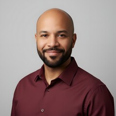 Confident portrait of a smiling young adult man in a maroon shirt against a clean neutral background, showcasing modern professional style, friendly expression, and studio lighting ideal for business 