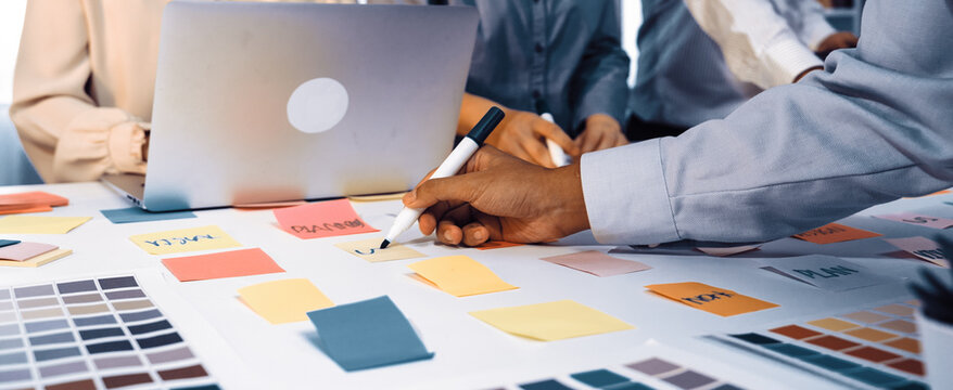 A dynamic team brainstorming session showcases creative ideas using sticky notes and color swatches on a desk, highlighting collaboration and project planning at work. SACTR - Powered by Adobe