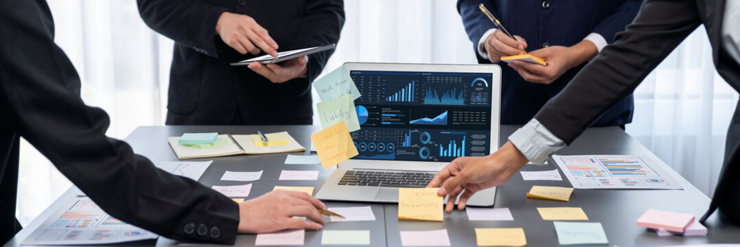 Analyst team use sticky note for creative and analytic brainstorm for business idea with BI data dashboard on laptop screen. Analysis financial data visualization tech for marketing strategy. Prodigy - Powered by Adobe