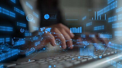 A business professional types on a keyboard while surrounded by blue digital data visualizations...