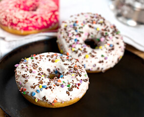 Donuts with sprinkles, delicious doughnuts on rustic table, American donuts for pleasure