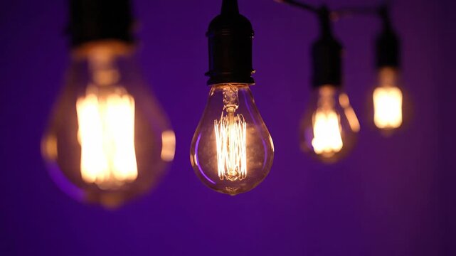 Glowing vintage light bulbs against a purple background in a row.