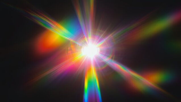 Abstract bright multicolored lens flare starburst featuring radial rainbow spectrum rays and light refraction against a pitch black background

