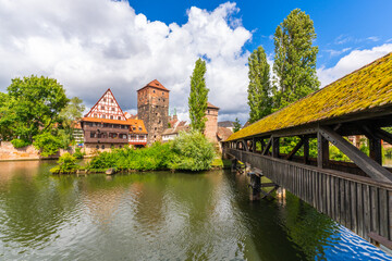 Obraz premium Old Town of Nuremberg. Weinstadel Building, Henkerbrucke Bridge and Henkerturm Tower on Summer Sunny Day. Pegnitz River. Franconia, Germany. Wide Shot