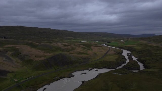 Aerial winding river through Icelandic hills
Drone view of a winding river cutting between dark rolling hills and green patches under overcast skies in Iceland, 2025
