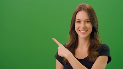 A cheerful young woman with brown hair points to the side against a green screen background. - Powered by Adobe