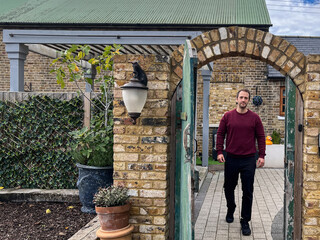 Man Walking Out Through Brick Garden Arch