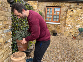 Man Placing Flower Pot in Garden