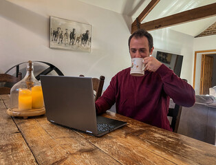 Man Enjoying Coffee While Working on Laptop at Home