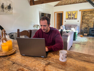 Man Working on Laptop at Rustic Wooden Table in Cozy Home