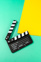 A close up shot of a clapperboard against a vibrant background of green and yellow, capturing the essence of filmmaking.