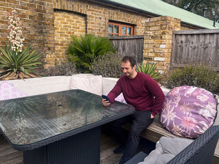 Man Sitting on Patio Bench Using Smartphone