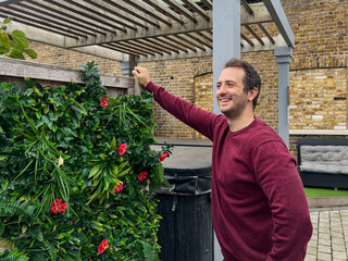 Smiling Man Standing by Green Garden Wall