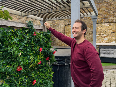 Smiling Man Standing by Green Garden Wall
