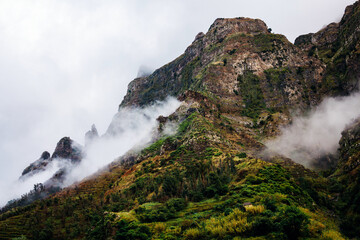 Majestic mountain landscape shrouded in mist, showcasing rugged cliffs and lush greenery, creating a serene and dramatic natural environment with captivating beauty