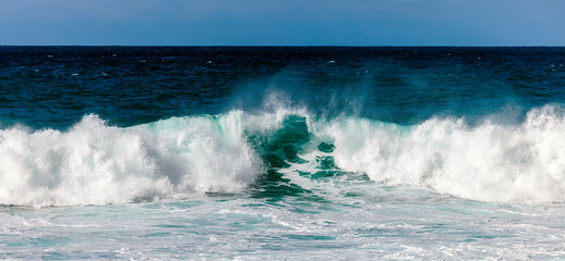 Powerful ocean waves crashing against the shore, creating a dynamic scene with foamy white surf and deep blue water, capturing the essence of nature's beauty and energy