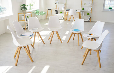 Chairs circle in bright meeting room interior. Minimalist room with white chairs and windows. Ideal for therapy session groups, workshops, business training. Symbolizes unity, support, open dialogue.