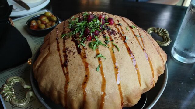 fancy elaborate fattoush salad inside a fried crispy pita bread shell being broken before eating with a spoon (middle eastern lebanese israeli syrian appetizer with pomegranate molasses and seeds)