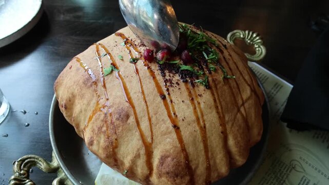 fancy elaborate fattoush salad inside a fried crispy pita bread shell being broken before eating with a spoon (middle eastern lebanese israeli syrian appetizer with pomegranate molasses and seeds)