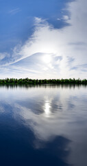 Fototapeta premium Serene Lake Landscape With Bright Sky And Reflective Water Under Lush Tree Line
