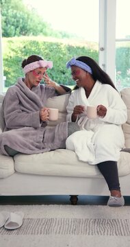 Vertical video: Diverse female friends wearing patches chatting on sofa during spa sparking giggles