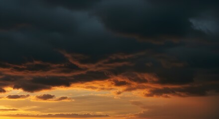 Fototapeta premium Dramatic dark clouds meet golden sunset light for stunning atmospheric background