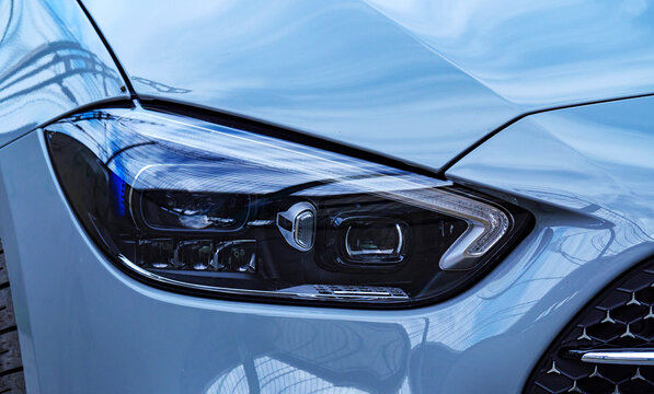 Detailed view of a sharp led headlight on a light blue modern car showing the complex internal structure and daytime running light signature