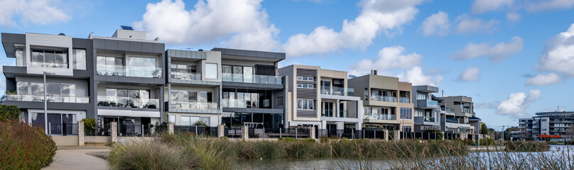 Modern lakeside residential apartment buildings in Caroline Springs, Victoria, featuring contemporary façades, balconies, and waterfront pathways. Suburban density, and planned community living.