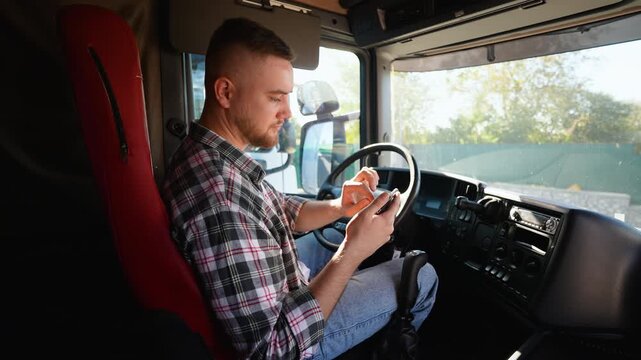 Truck driver using smartphone inside lorry cabin