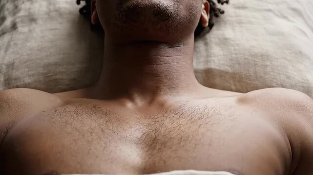 Close up of a man's chest and neck covered in a fine exfoliant scrub with gentle natural lighting on a neutral linen background for skincare advertisement and spa