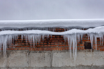 Background - grey cloud sky and old shabby brick wall with icicles