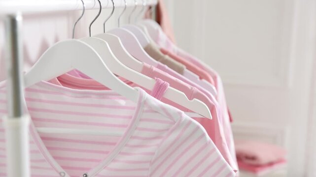 Woman hanging t-shirt on rack indoors, closeup. Camera moving in