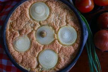 Naklejka premium Traditional torta capixaba, a classic Brazilian seafood and vegetable pie typically served during Holy Week in Espírito Santo. Presented in a rustic clay pan, the dish features its iconic onion rings 