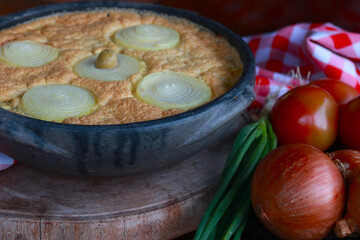 Traditional torta capixaba, a classic Brazilian seafood and vegetable pie typically served during Holy Week in Espírito Santo. Presented in a rustic clay pan, the dish features its iconic onion rings 