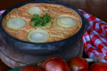Traditional torta capixaba, a classic Brazilian seafood and vegetable pie typically served during Holy Week in Espírito Santo. Presented in a rustic clay pan, the dish features its iconic onion rings 