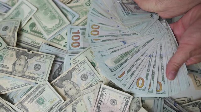 fingers grasping currency amidst scattered bills, vibrant scene of cash being held in celebratory manner, energetic closeup capturing hands with bills and festive winnings atmosphere