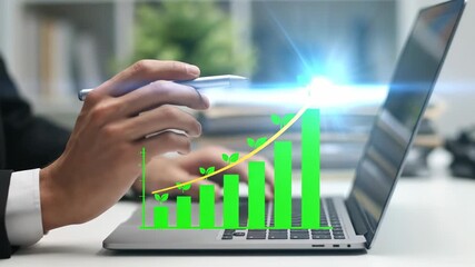 Man in suit using laptop with green growth bar graph on screen, symbolizing business growth and financial success in an office setting. - Powered by Adobe