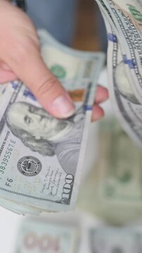 vertical screen hands exchanging money, individuals exchanging physical cash with widespread bills visible behind them, people engaged in financial exchange involving cash with bills spread