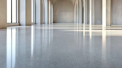A vast, empty interior space with a highly reflective, speckled concrete floor and a series of arched openings supported by columns.